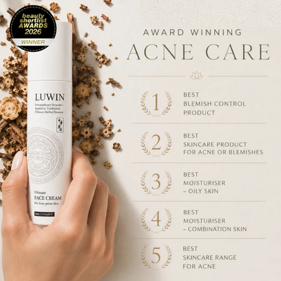 A hand holds a white bottle of LUWIN Ultimate Face Cream against a light beige background with dried Chinese herbs and award text reading 'Award Winning Acne Care' and five individually listed award-winning titles.
