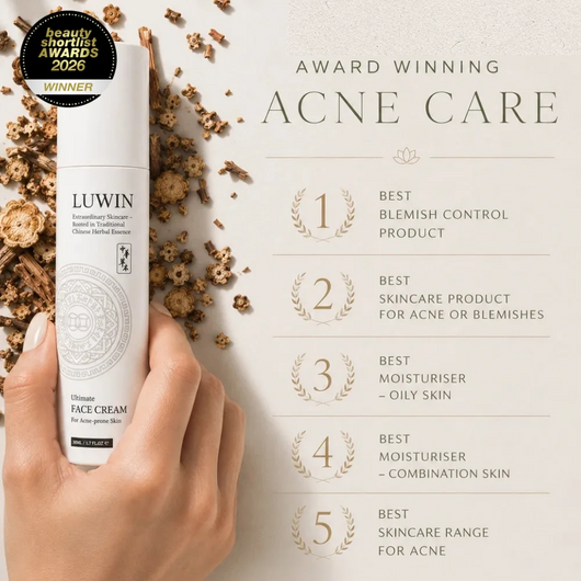 A hand holds a white bottle of LUWIN Ultimate Face Cream against a light beige background with dried Chinese herbs and award text reading 'Award Winning Acne Care' and five individually listed award-winning titles.