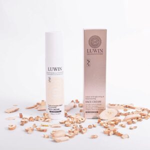 Best for brightening in top left corner of an image with LUWIN Power of brightening and rejuvenating face cream white bottle and silky light brown box next to each other surrounded by chinese herbs.